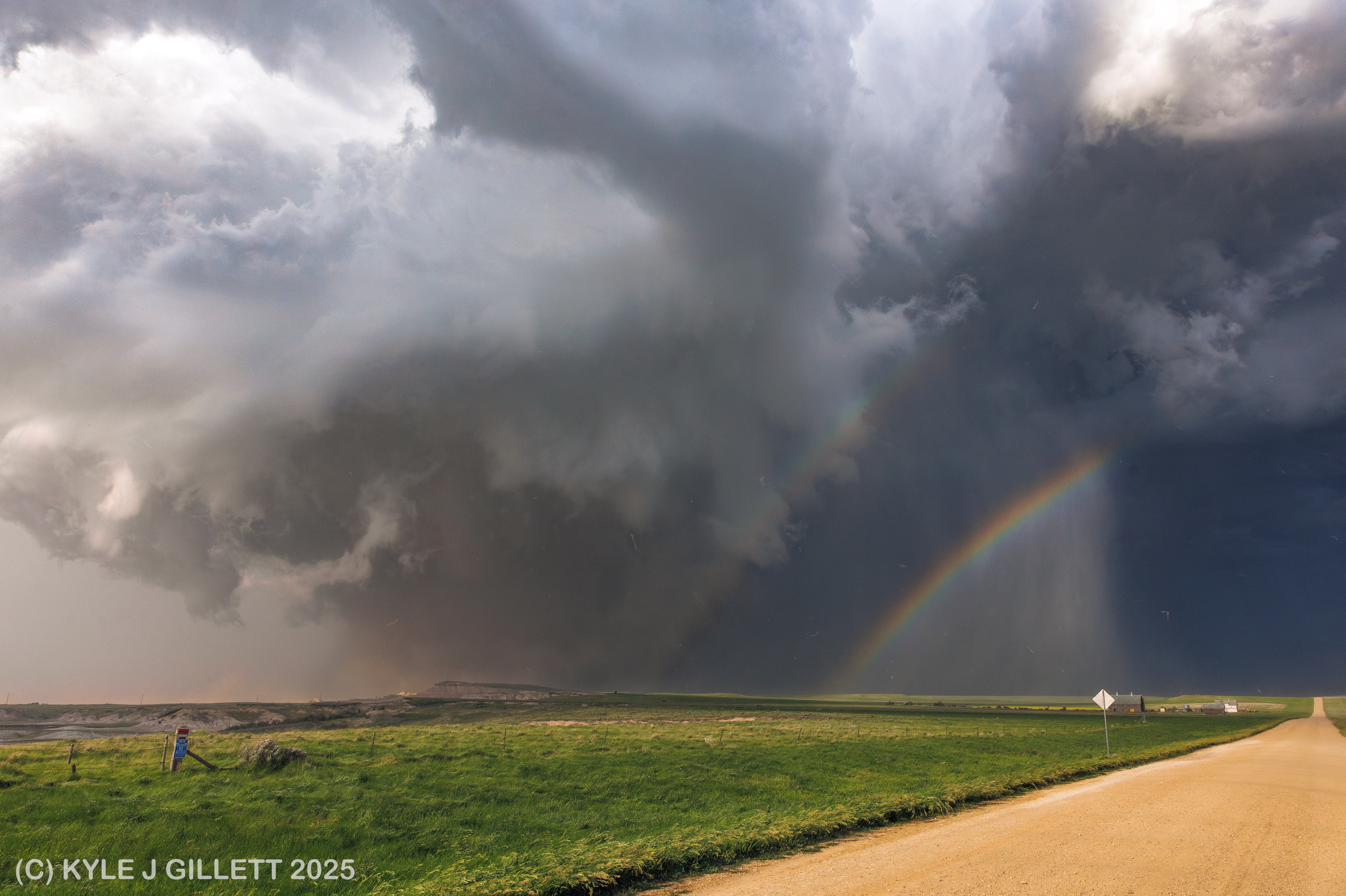 Rain and dust beneath the tornado with a double rainbow.